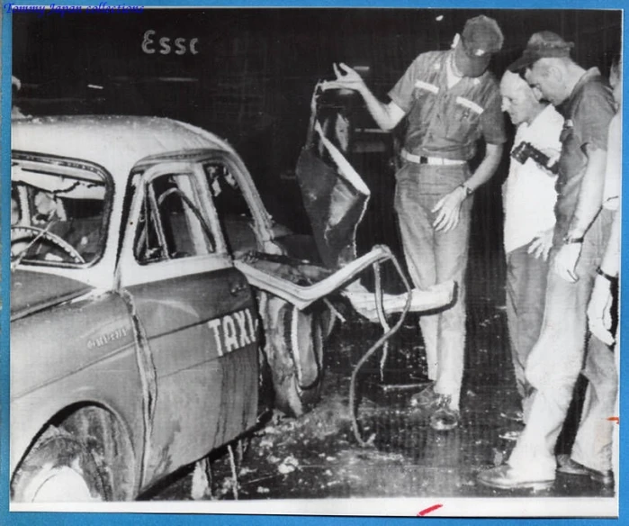 two men looking at a car that was badly damaged