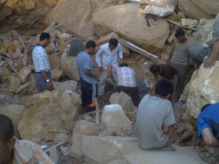 a group of men digging through rocks in an open area