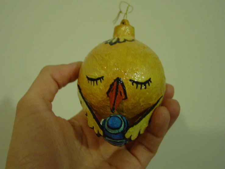 hand holding a yellow decorated ornament with eyes closed