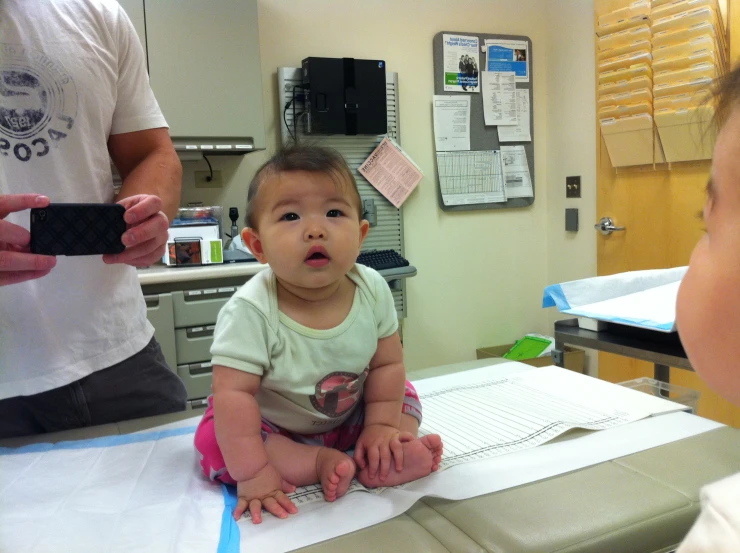 a little baby sitting in a hospital bed next to a woman