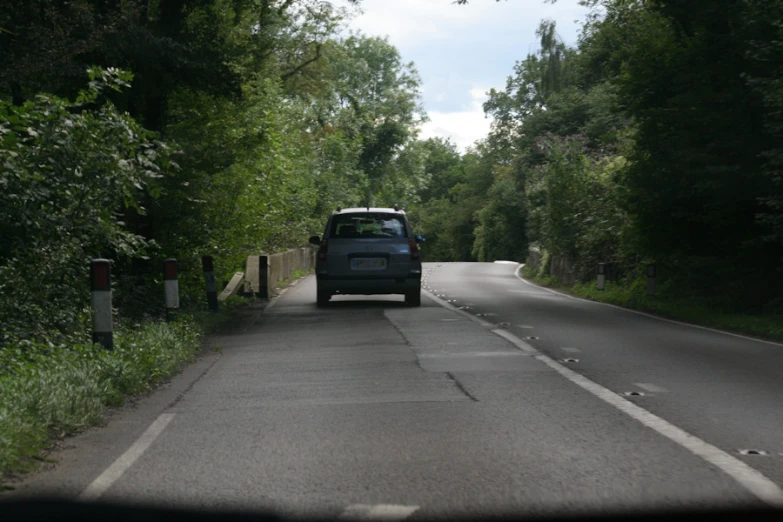 a vehicle driving down the road between trees