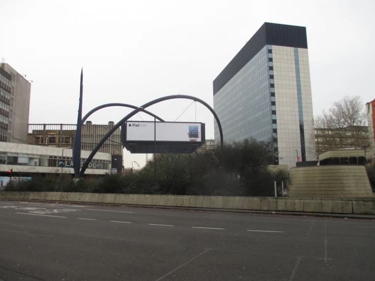 a billboard near a street and buildings near an empty road