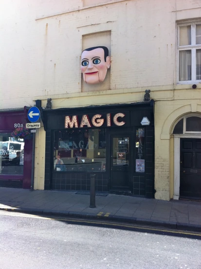 a large head on the side of a storefront in a town