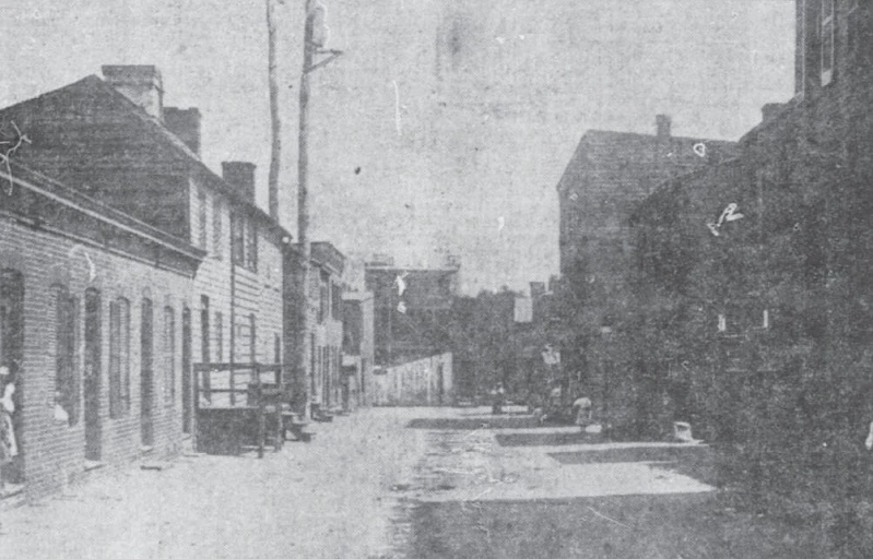 an old black and white po with people in front of houses