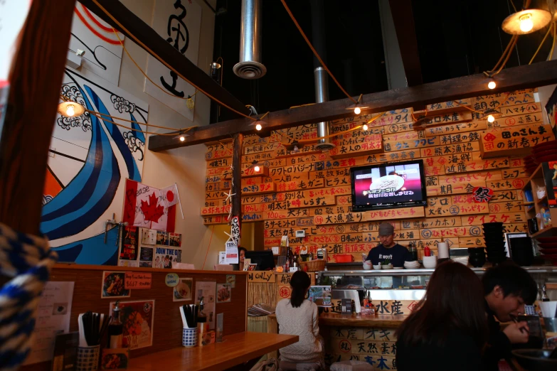 a japanese restaurant with customers seated at a bar