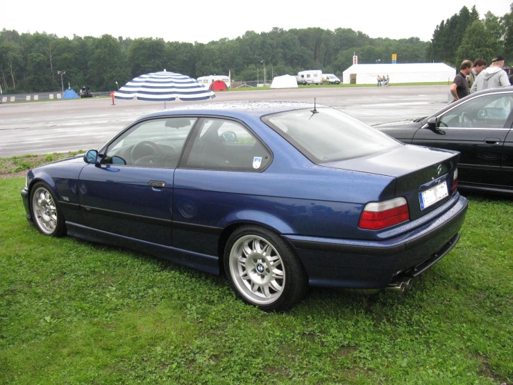 blue car parked near two other cars on grass