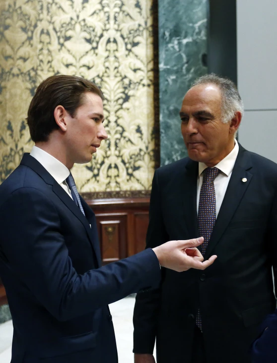 a young man in business attire talking to another man