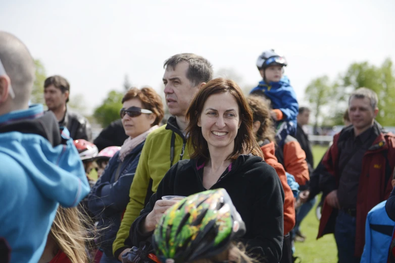 a crowd of people stand together smiling, wearing helmets