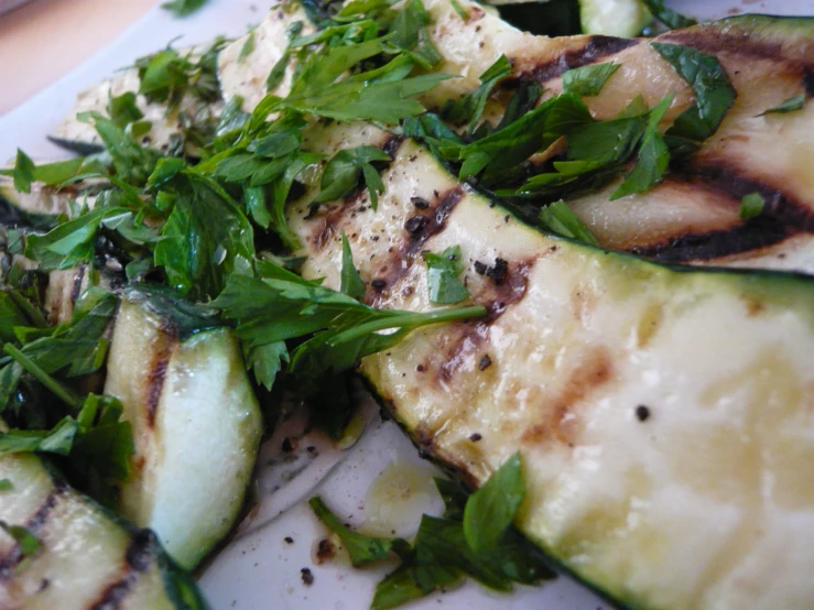 a white plate topped with cucumbers and greens