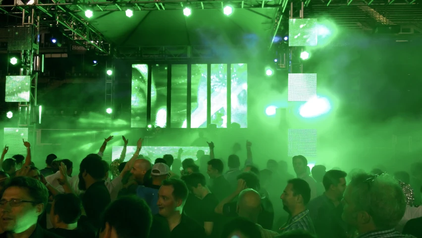 a crowded nightclub with people standing around and green lights in the background