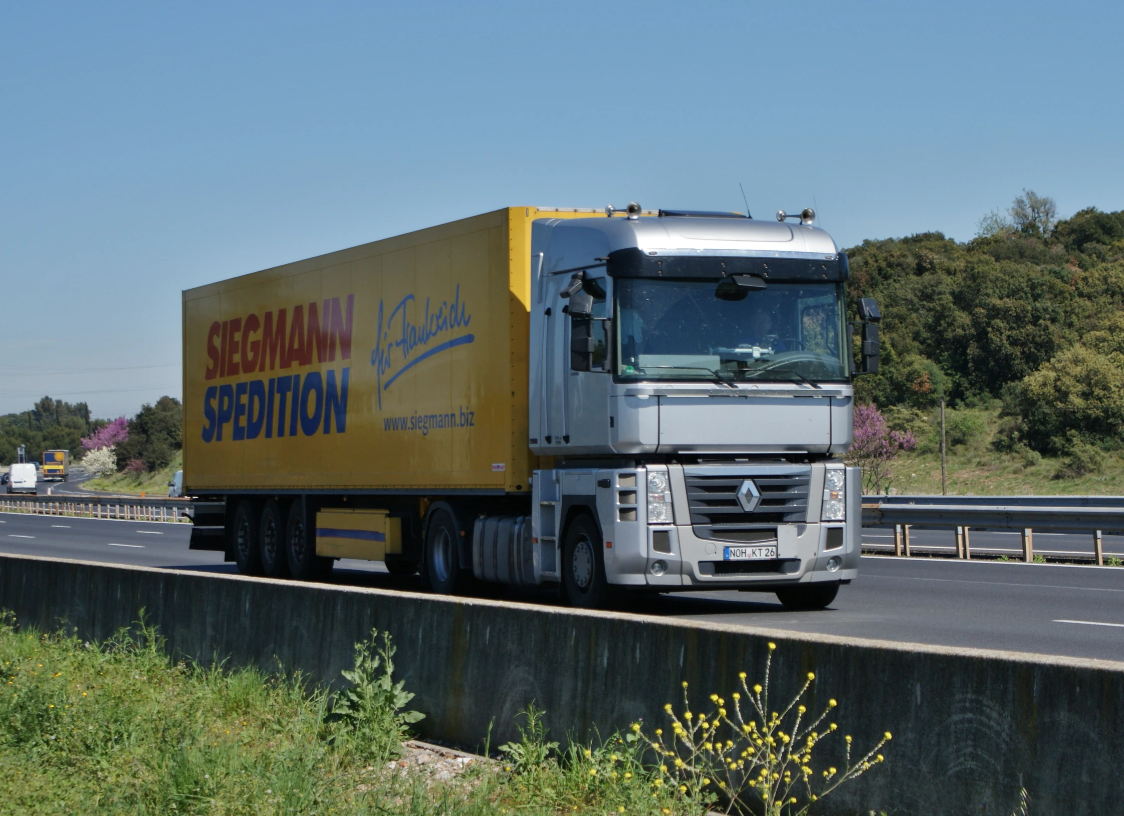 a yellow truck travels along a highway by grass