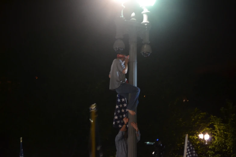 two men standing next to each other on top of a pole