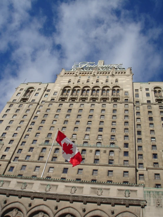 a very tall building with lots of windows and some canadian flags flying in the wind