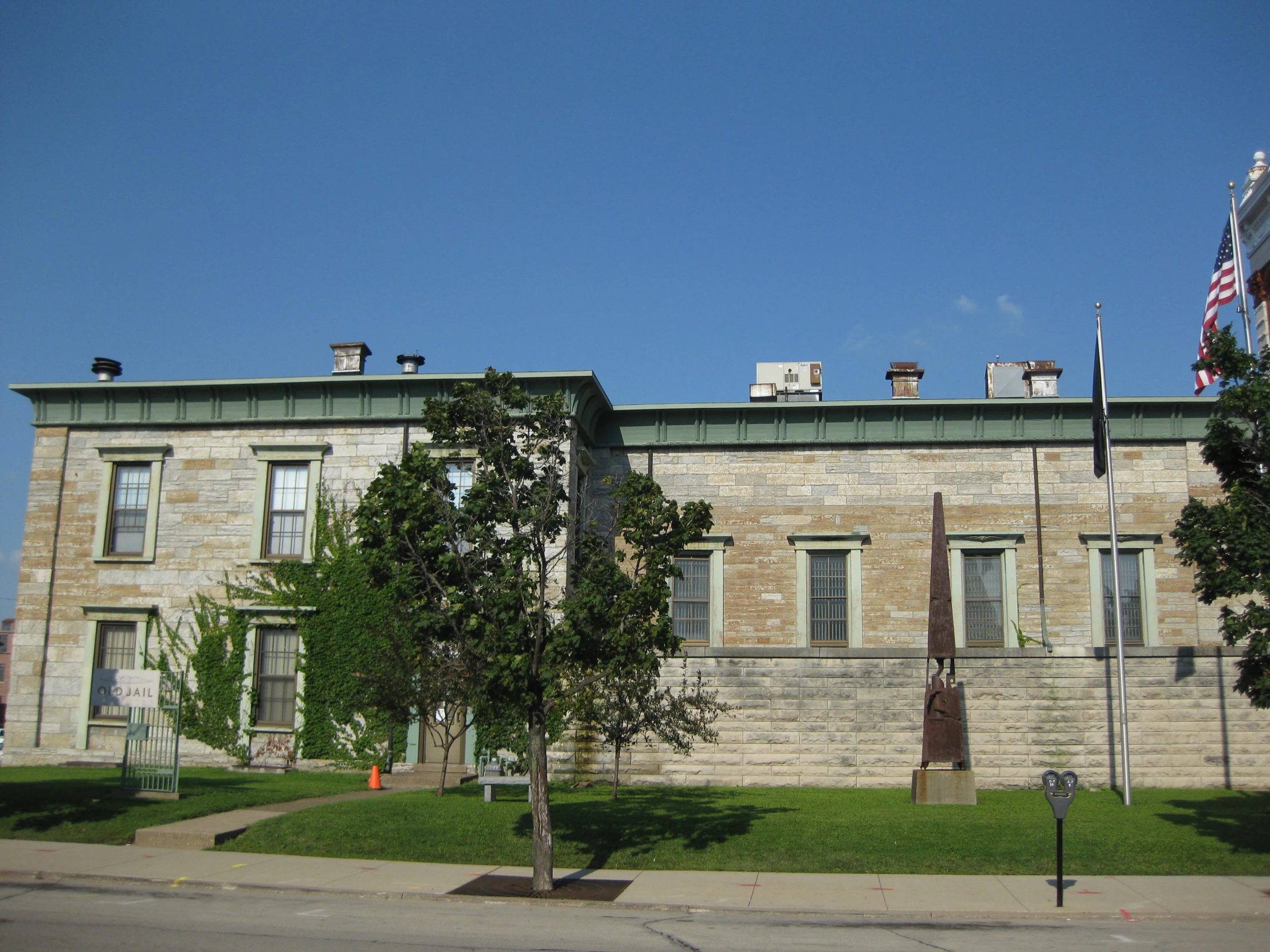 an old brick building with flag poles and tree in front of it