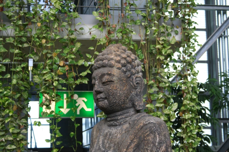 there is a buddha statue and a green sign behind it