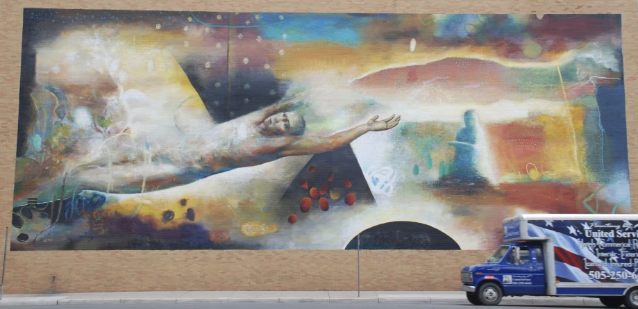 a delivery truck is parked in front of a large mural of a man's hand