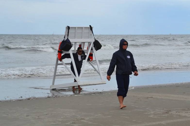 man walking towards lifeguard chair on beach during daytime