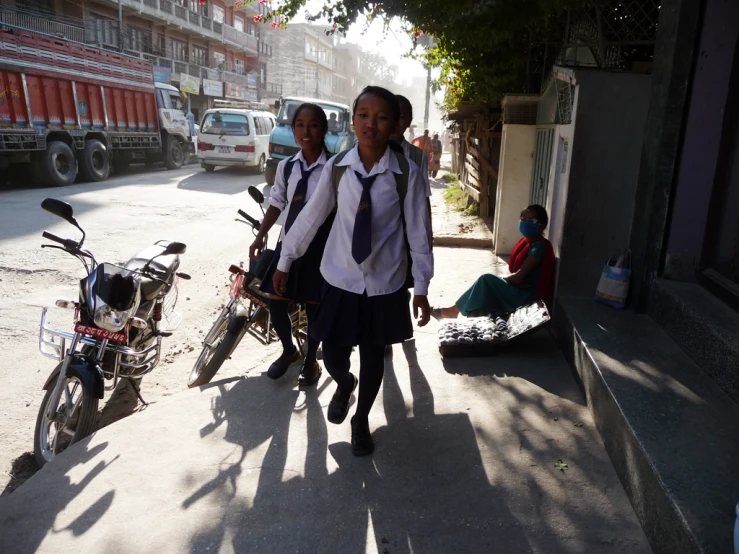 school children dressed in uniforms, standing by their bikes