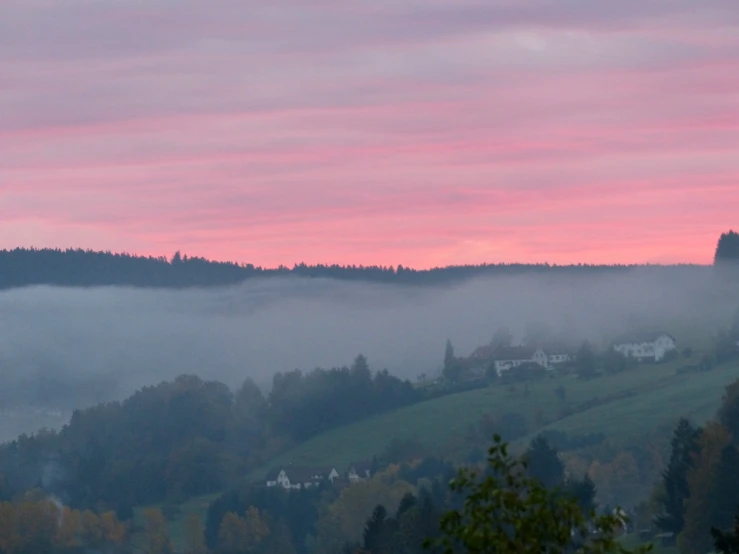 a foggy mountain with many houses and trees