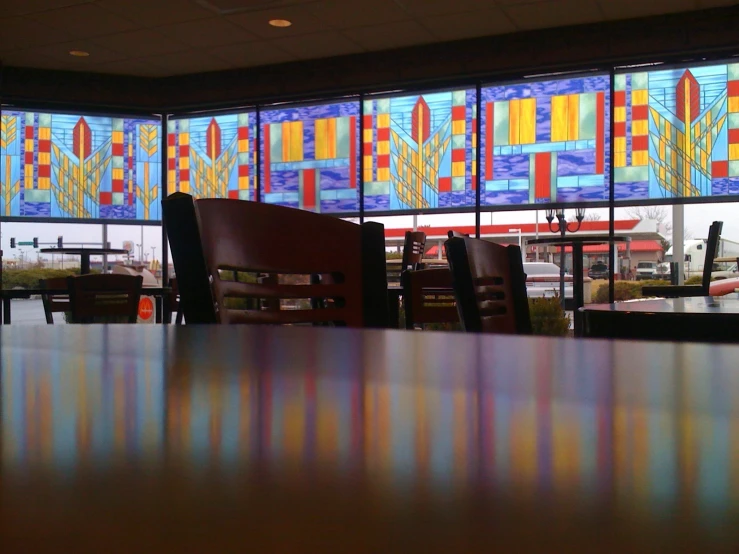 the dining room tables and windows with multiple colorful stained glass panels