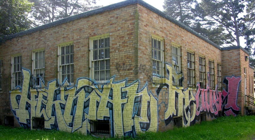 a brick building covered in graffiti next to a tree