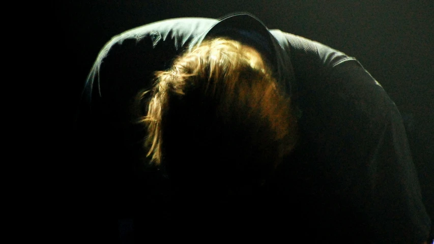 a woman is shown sitting down in the dark