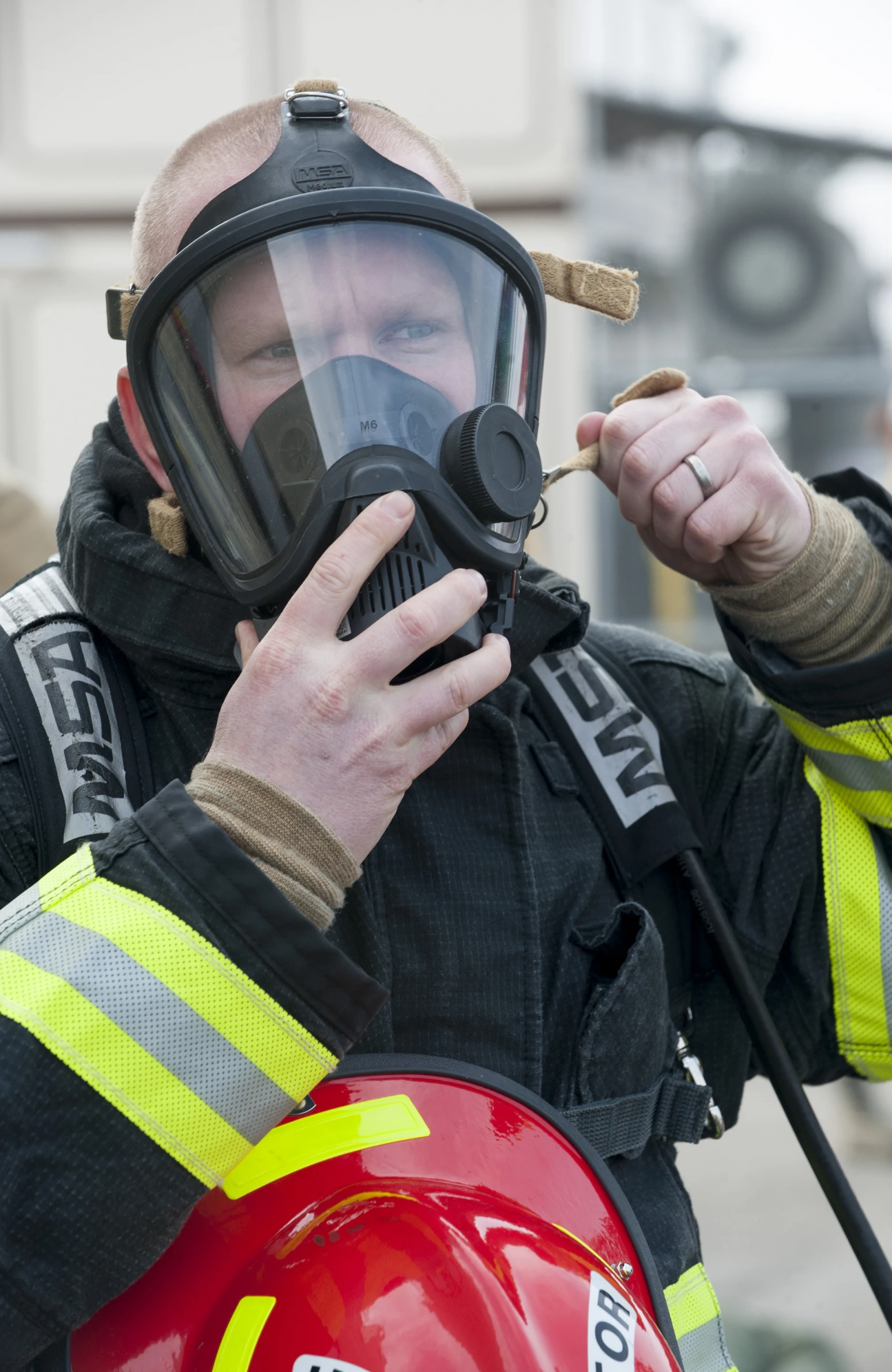 a fireman in his safety gear holding a lighter to a piece of metal