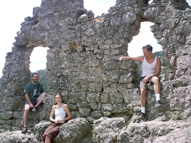 three people sitting on large rocks in the ruins