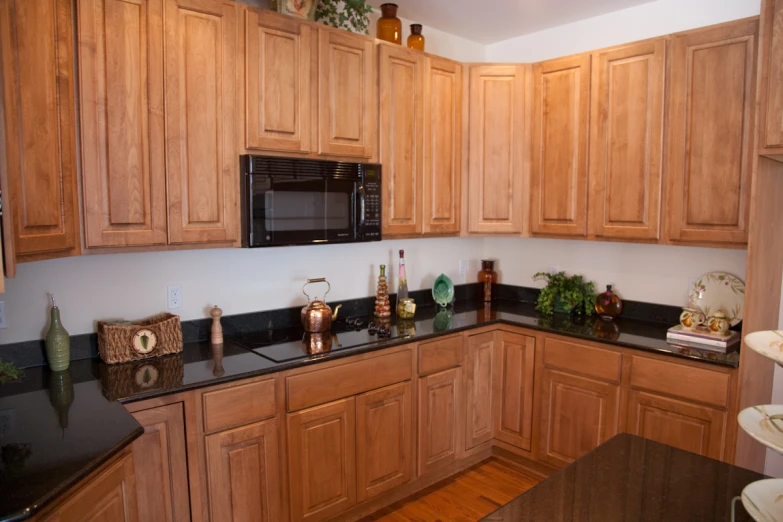 a black counter top next to a brown wooden cabinet