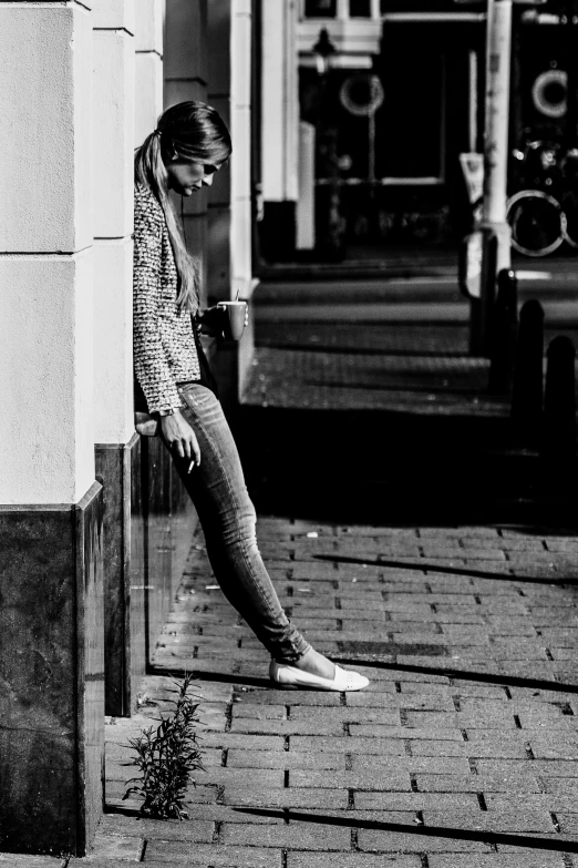 the woman is standing by the wall in the street