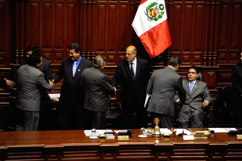 men in suits and ties stand next to the mexican flag