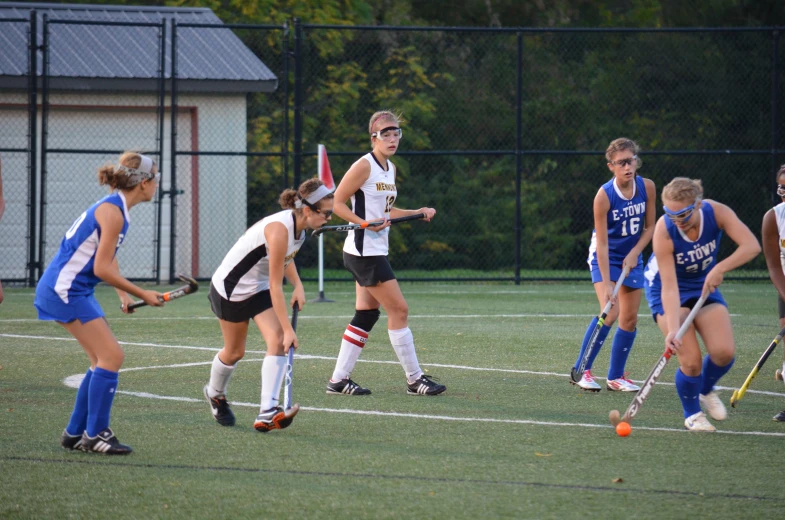 a group of young women on a field playing hockey