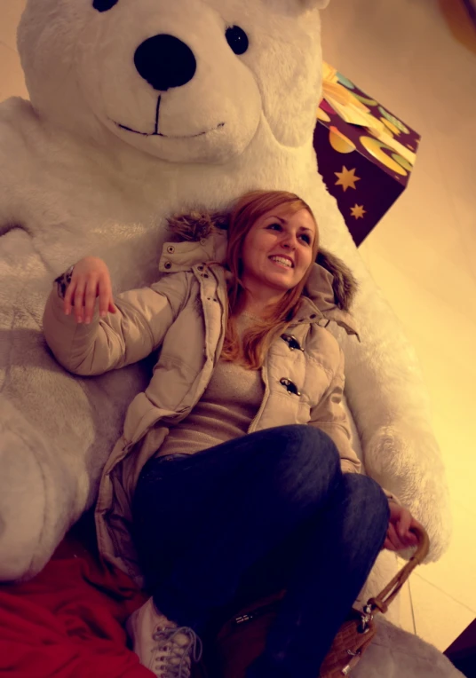 a woman sitting on a giant teddy bear