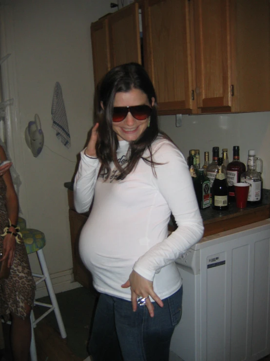 a pregnant woman with sunglasses posing for a po