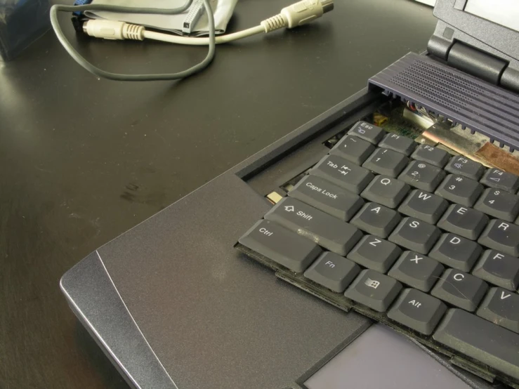 an open laptop computer on a desk with cords and a cord