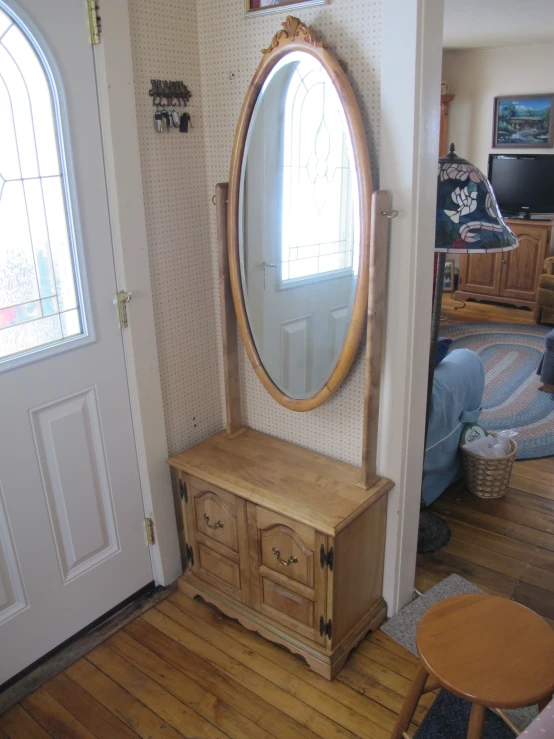 an old fashioned wooden cabinet and a big round mirror in a room