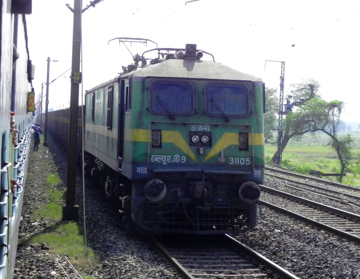 a green train traveling down tracks next to a fence