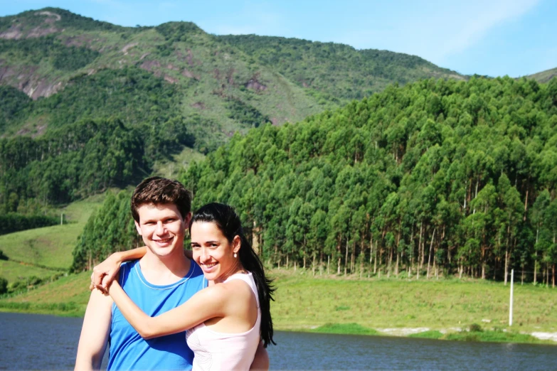 two young people standing close together by the water