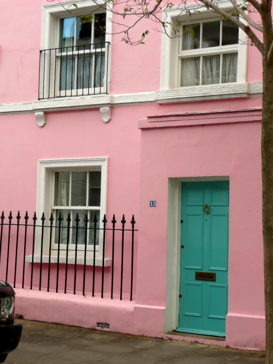 a car parked next to a pink building and a blue door