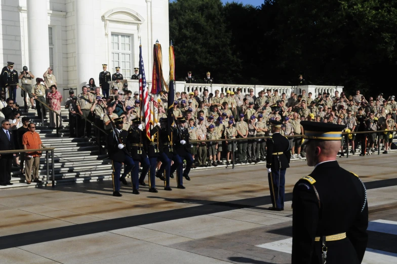 soldiers stand at attention in front of a large crowd