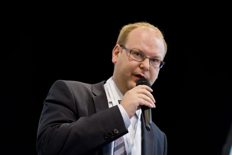 a man in a suit and tie speaking into a microphone