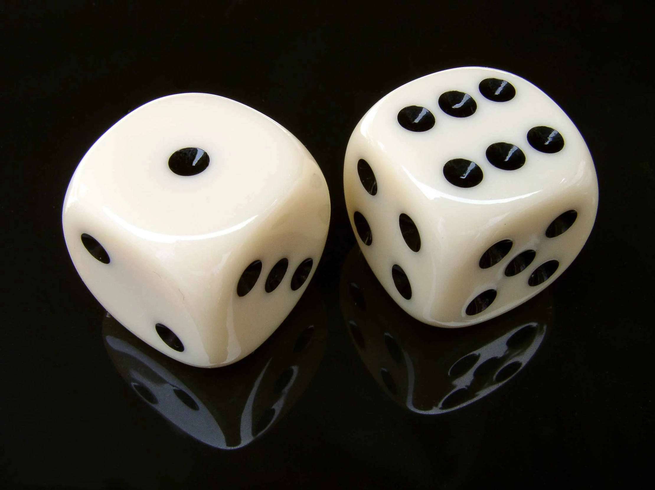 two white dices sitting side by side on a black surface