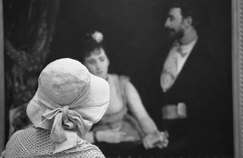 two women are wearing hats, in front of an old pograph