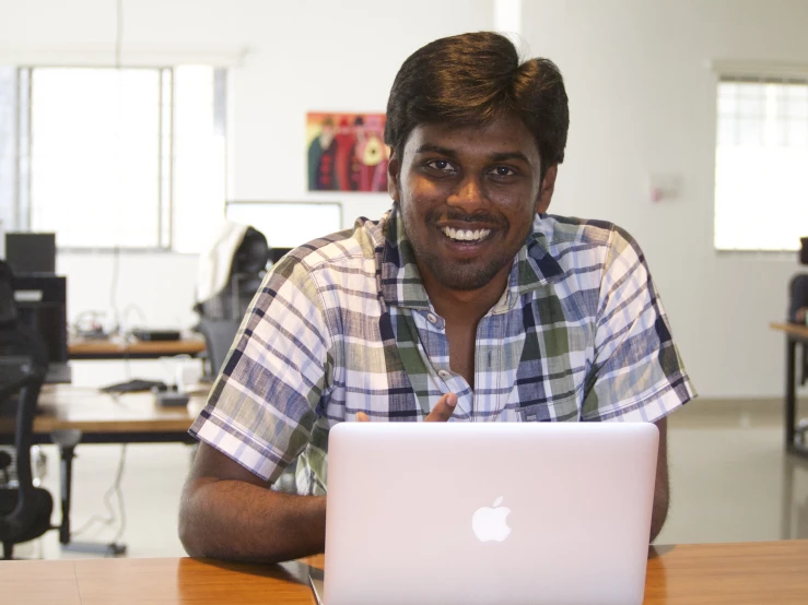 a man smiles while looking at his apple computer