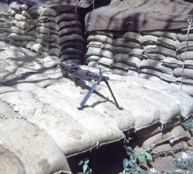 the machine gun lies on top of the pile of sandbags