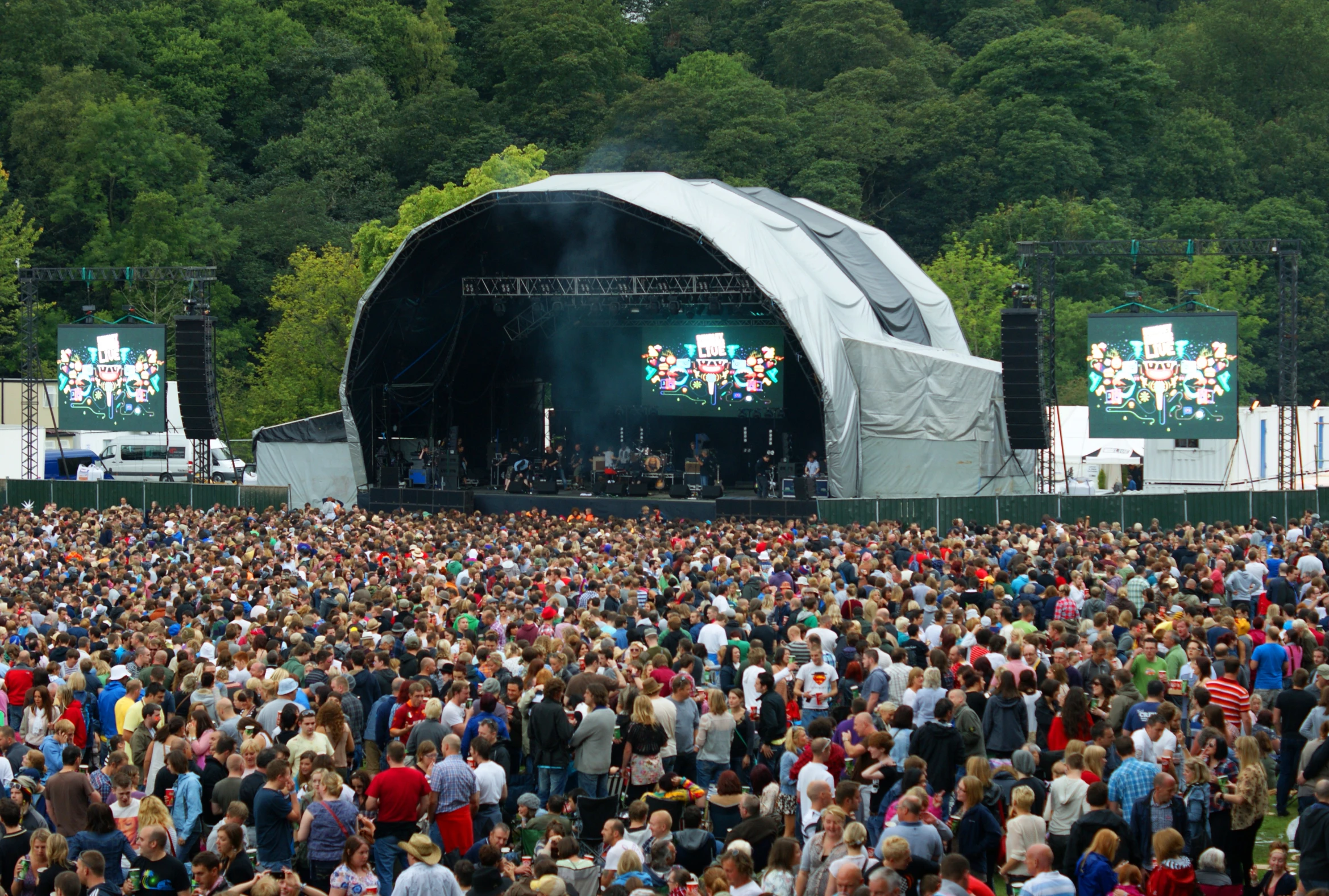 a large crowd gathered together in front of a stage with a number of people