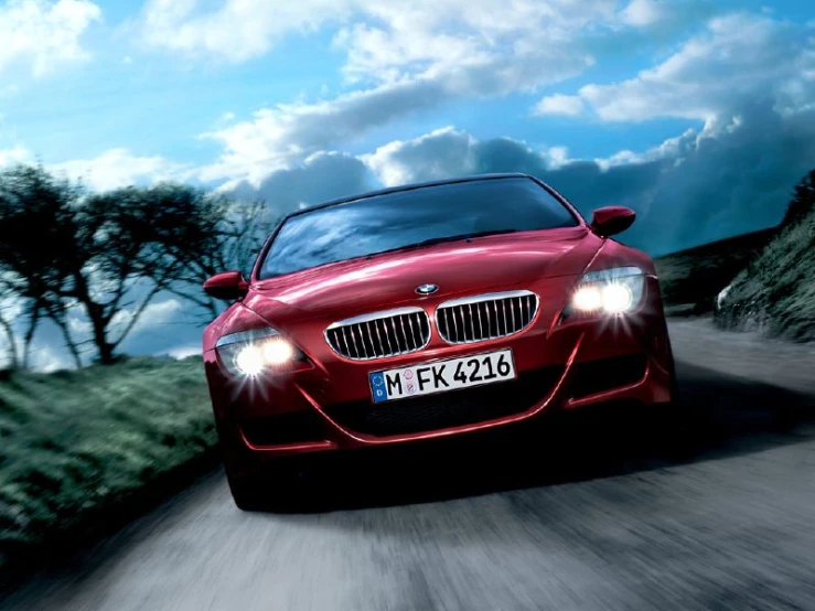 the bmw z4 has bright red paint and is driving down a hill