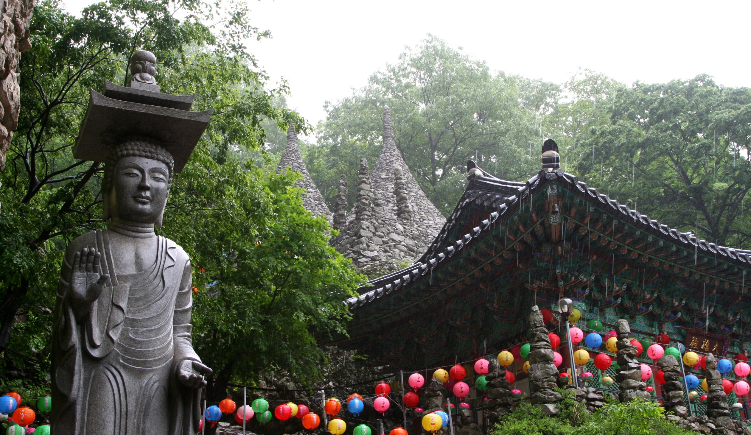 two buddha statues in the foreground surrounded by colorful balloons