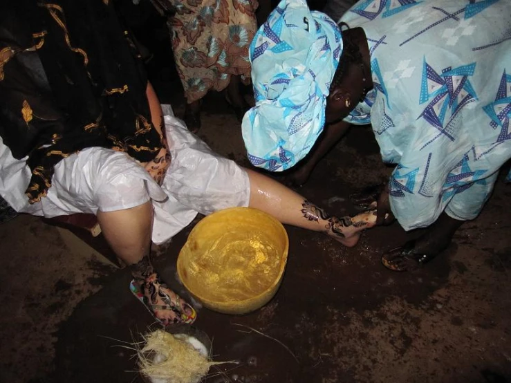 two women are bending over to scoop up soing