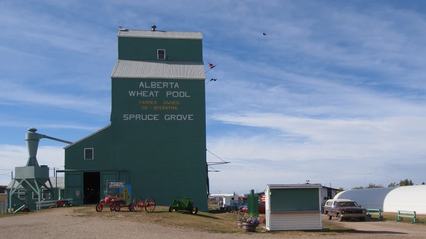 an old green building with a red tractor in front